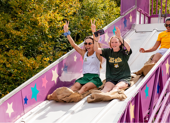 Group of people posing together at a homecoming tailgate on campus.