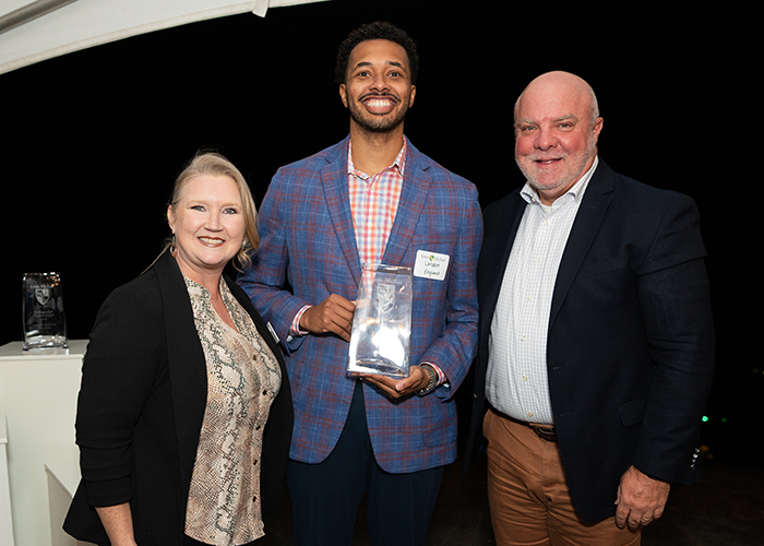 London England holds his award while standing with President Lee King and Alumni Board President Tennille Sherrill.