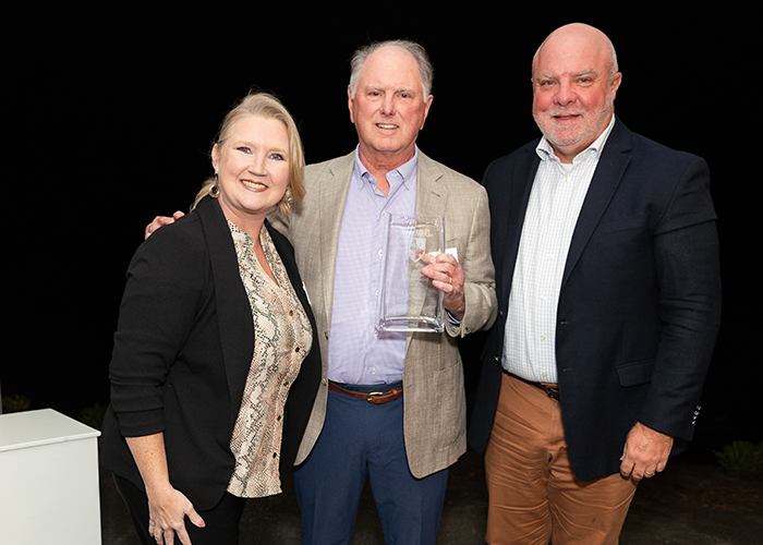 Thomas Brigham holds his award while standing with President Lee King and Alumni Board President Tennille Sherrill.