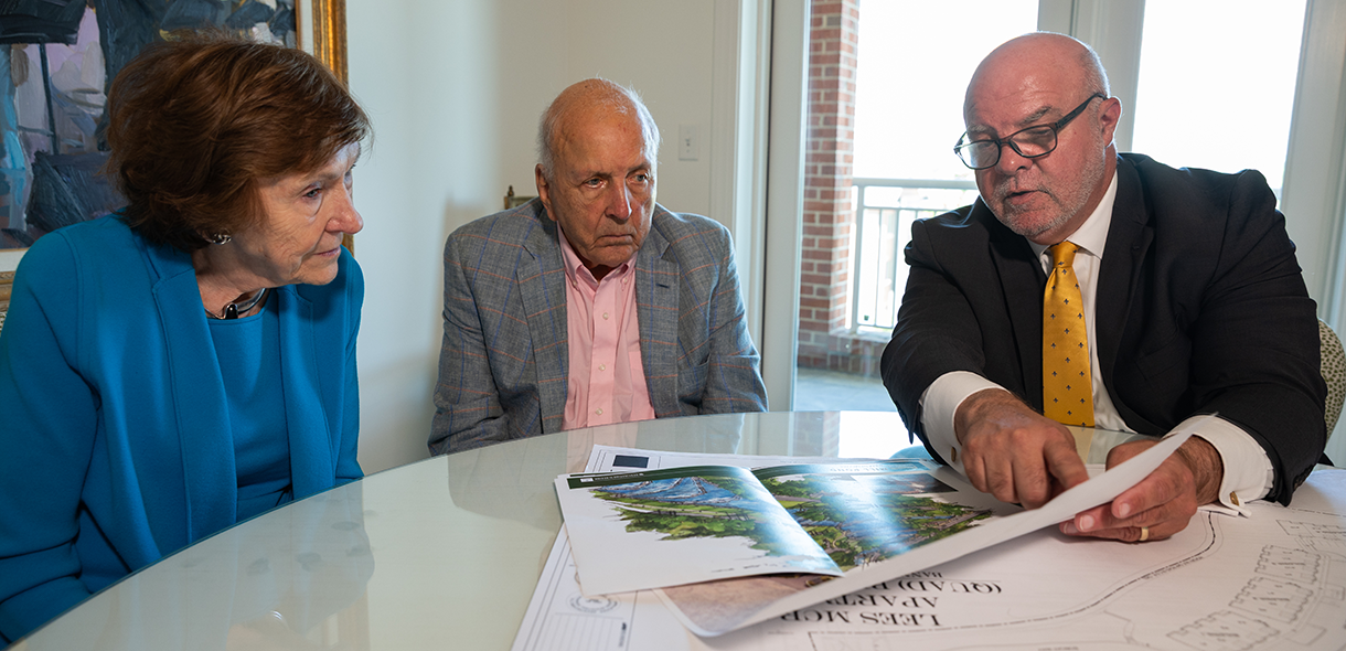 Smoky and Margaret Bissell sit at a table with President Lee King and examine building plans.