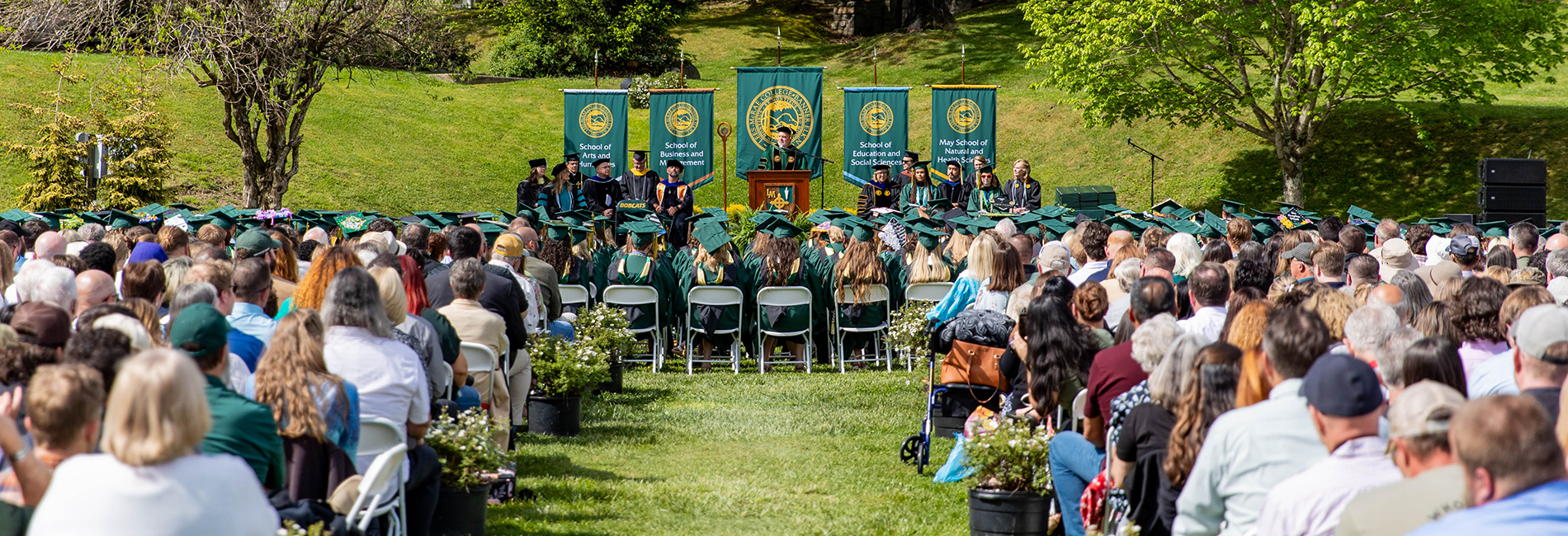Graduates and families sit on Tate Lawn while President King addresses the crowd from a podium.