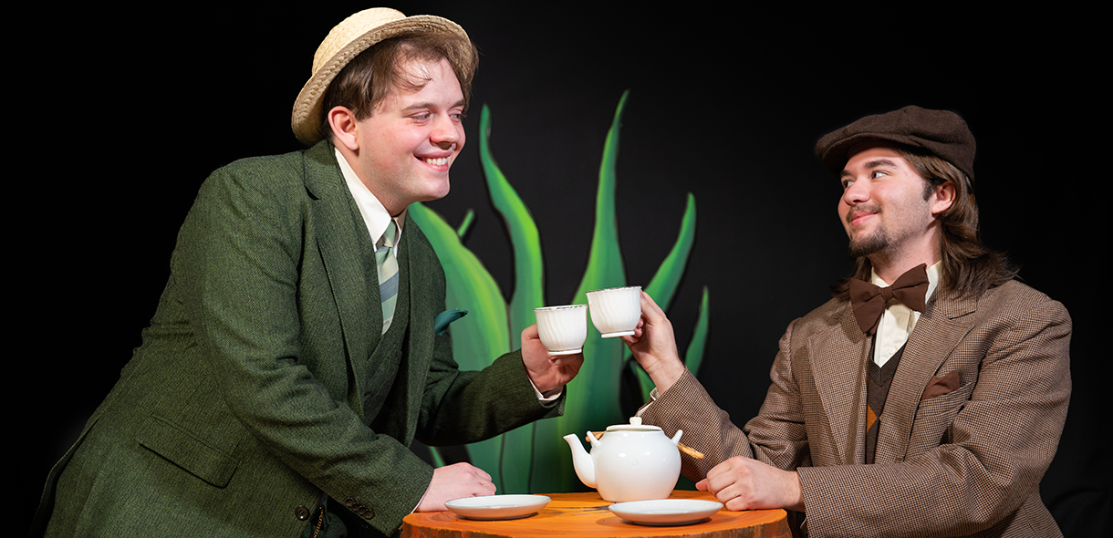 Student actors portraying frog and toad clink teacups.