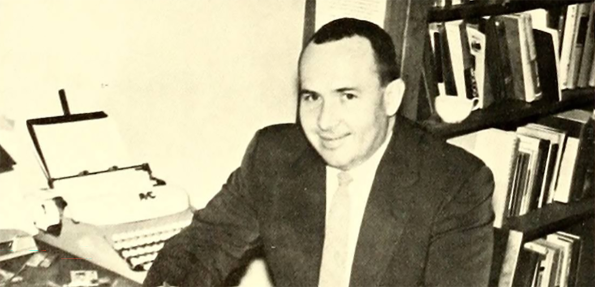 Lewis Hall sits at his desk, 1962.