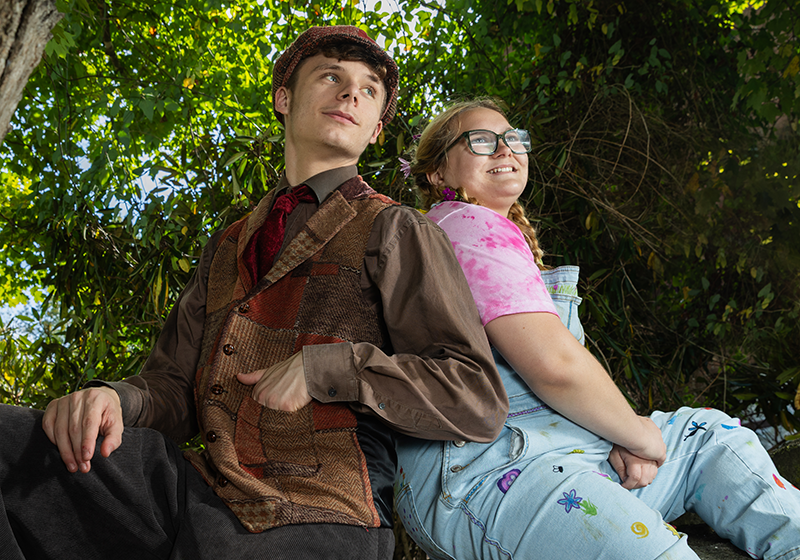 Two student actors in costume sit in a tree.