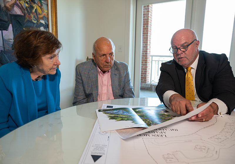 Smoky and Margaret Bissell sit at a table with President Lee King and examine building plans.