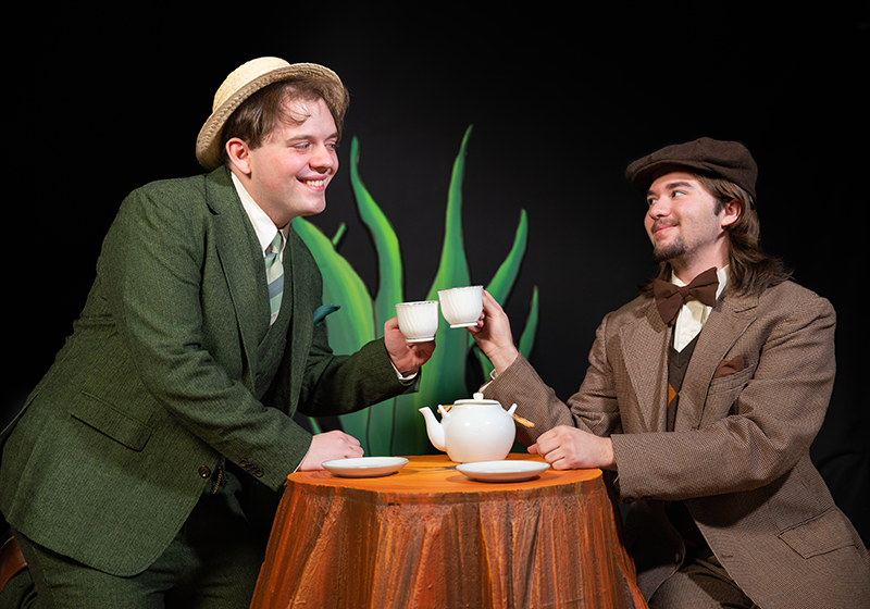 Student actors portraying frog and toad clink teacups.
