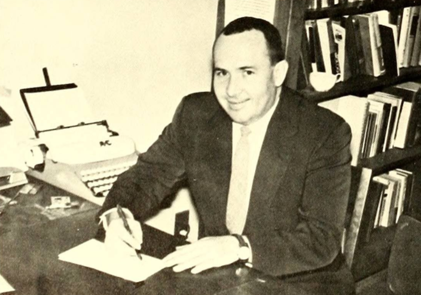 Lewis Hall sits at his desk, 1962.